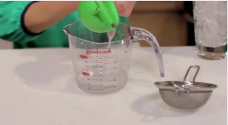 A green citrus press over a measuring cup, from the paper’s lime-juice example